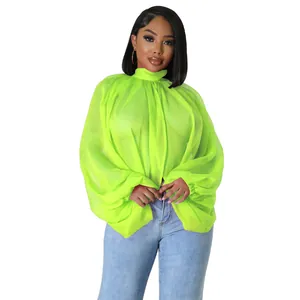 Modella con top in chiffon verde neon trasparente con voluminose maniche a pipistrello.