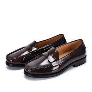 Primer plano de mocasines penny en cuero marrón oscuro pulido con costuras elegantes