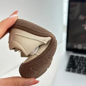 Gros plan d'une sandale bébé beige montrant une semelle souple très flexible.