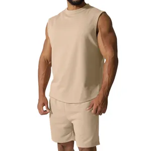 Muskulöses Model in einem beigen ärmellosen Sportset mit Tanktop und passenden Shorts