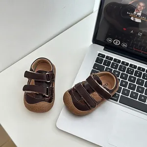 Vue détaillée de sandales en cuir marron pour tout-petit avec velcro près d'un portable