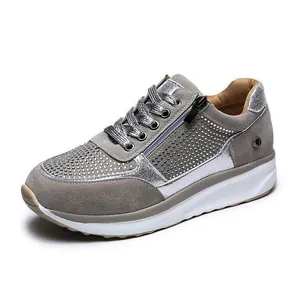 Dettaglio di sneakers con zeppa grigie con decorazioni in strass e cerniera laterale