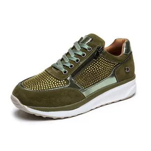Primo piano di sneakers platform verde oliva con strass dorati e chiusura a zip laterale.