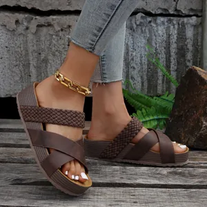 Detailweergave van bruine damesplatformsandalen met gevlochten en gladde bandjes.