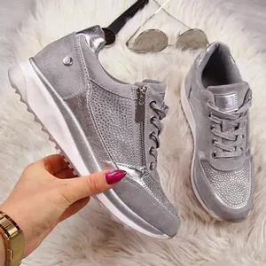 Primo piano di sneakers silver platform con dettagli in strass scintillanti e zip laterale.