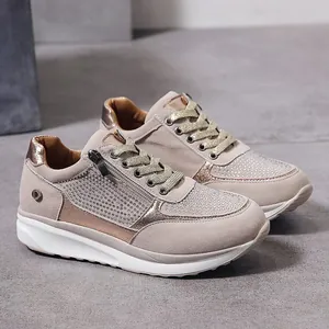 Primo piano di sneakers chunky beige con decorazioni in strass e cerniera laterale