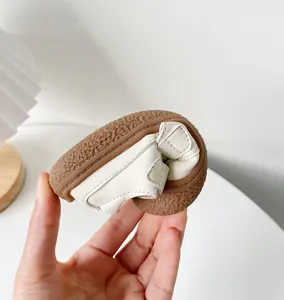 Gros plan montrant la grande souplesse et la semelle souple de ces sandales crème pour bébé
