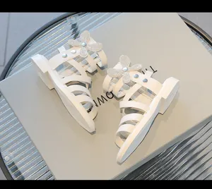 Vista detallada de las sandalias romanas blancas para niñas con mariposa de strass