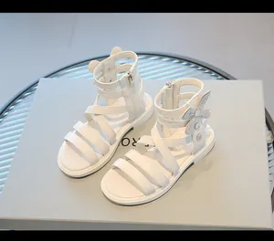 Detalle de sandalias romanas altas blancas para niñas con lazo de diamantes brillantes