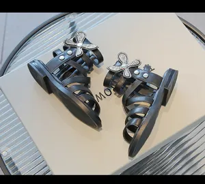 Detalle de sandalias gladiadoras negras para niña con mariposa de diamantes brillantes