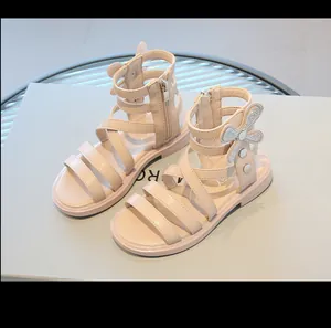 Elegantes sandalias romanas altas para niña con detalle de lazo de pedrería brillante.