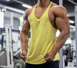 Detailed view of yellow cotton stringer tank top on muscular male athlete in gym
