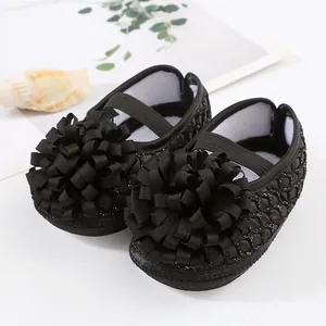Gros plan détaillé sur d'élégantes chaussures de bébé noires avec de grandes fleurs.