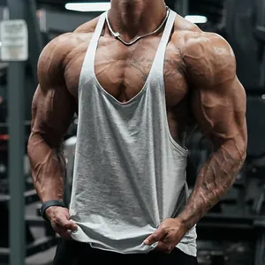 Detailed view of a grey cotton stringer tank top on a muscular fitness model in a gym.