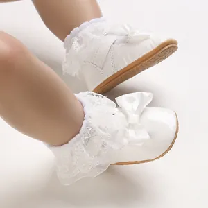 Primo piano di scarpe bianche per bambina con volant in pizzo e fiocchi di raso eleganti.