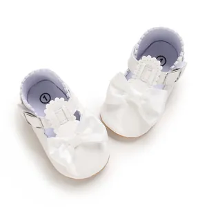 Dettaglio scarpe primi passi bianche per neonata con fiocco e fibbia