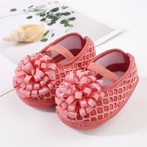 Gros plan de chaussures de princesse roses en maille pour bébé avec une grande fleur en ruban
