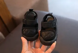 Macro view of black baby sandals with quilted velcro straps and soft non-slip soles