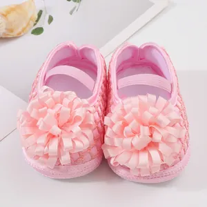 Gros plan de chaussures de princesse rose pour bébé avec grande fleur en ruban.