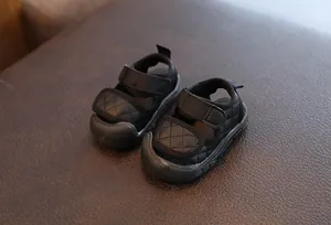 Detailed close-up of black quilted baby sandals with adjustable velcro strap closure.