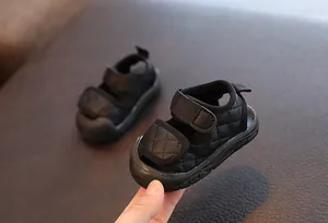 Close-up of black infant sandals with quilted pattern and hook-and-loop straps