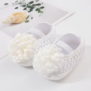 Gros plan d'élégantes chaussures de princesse blanches pour nouveau-né avec fleur en ruban