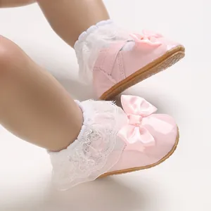 Dettaglio scarpe primi passi neonato in vernice rosa con pizzo e fiocco decorativo