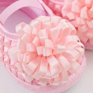 Détail macro de chaussures princesse bébé roses avec fleur en ruban doux à plusieurs couches