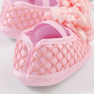 Détail de chaussures de princesse roses pour bébé avec grande fleur et résille