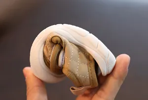Close-up showing the extreme flexibility and soft sole of the khaki baby sandal