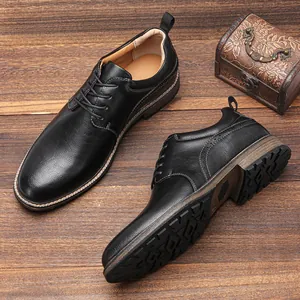 Scarpe derby da uomo in pelle nera su sfondo in legno con scatola decorativa.