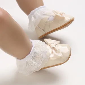 Vista dettagliata delle scarpe da bambina color crema con volant in pizzo e fiocco