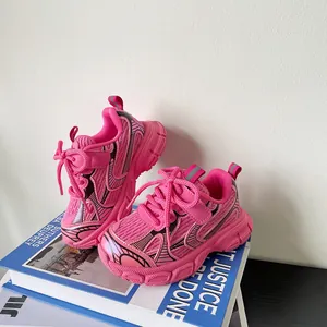 Detailed view of pink mesh toddler sneakers with chunky soles on a decorative book.