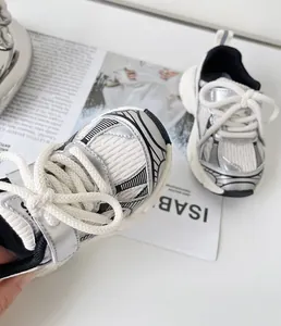 Detailed view of silver and white toddler sneakers featuring soft mesh and thick laces
