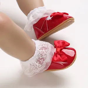 Dettaglio scarpe da neonata in pelle verniciata rossa con pizzo bianco e fiocco