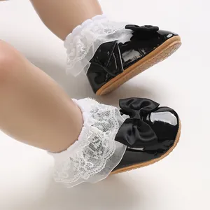 Dettaglio scarpe neonata in vernice nera con fiocchi di seta e volant in pizzo