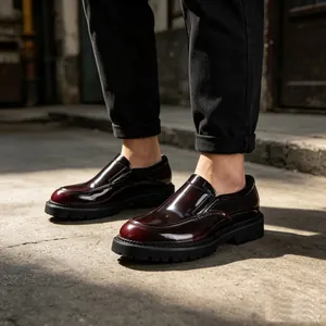 Detailopname van bordeauxrode laklederen herenloafers met een dikke zwarte rubberen zool