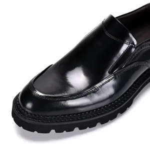 Gedetailleerde close-up van glanzende zwarte lakleren instappers met dikke zool en stiksels