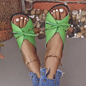 Sandalias de punta abierta verdes con detalle de lazo usadas por una modelo.