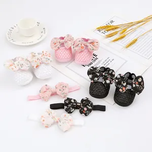Nahaufnahme von Babyschuhen mit Blumenschleife und passenden Stirnbändern in Rosa, Weiß, Schwarz.