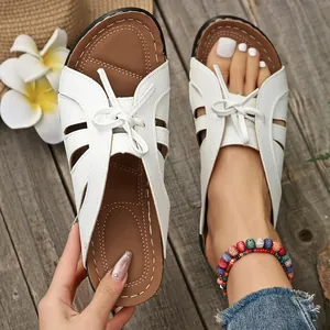 Primer plano de sandalias de cuña blancas con lazo elegante y diseño calado a la moda