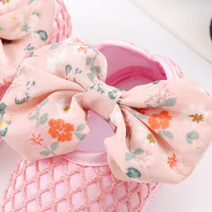 Detailaufnahme von rosa Babyschuhen mit Netzstruktur und einer großen Blumenschleife
