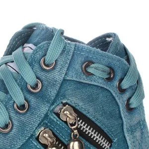 Macro view of blue denim high-top sneakers featuring stylish double zippers and eyelets.