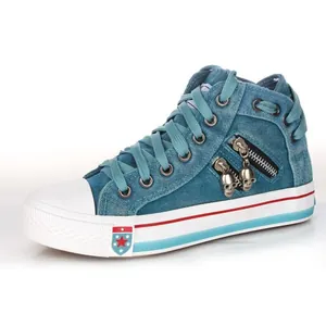 Side view of blue denim high-top canvas shoe with unique skull zipper charms