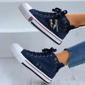 Detailed view of high-top denim sneakers featuring side zipper and skull charms.