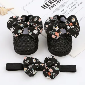 Nahaufnahme von Babyschuhen mit Blumen-Schleifen und passendem Stirnband in Schwarz