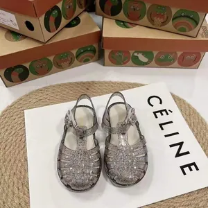 Detailansicht der glitzernden silbernen gewebten Jelly-Sandalen für Kinder auf Display