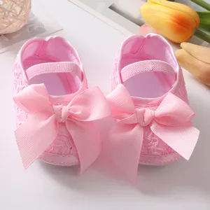 Detailansicht von rosa Spitzen-Babyschuhen für Neugeborene mit großer Satinschleife.