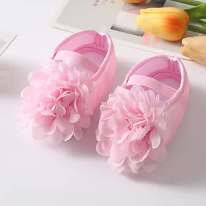 Dettaglio del grande fiore in tessuto rosa su scarpine morbide da principessa per neonati.