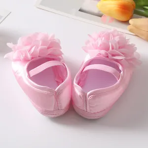 Primo piano di scarpe da principessa per neonata in raso rosa con un grande fiore